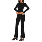 Woman in black long-sleeve top and flared pants, wearing black platform heels. Fashionable outfit, modern style, women's clothing.