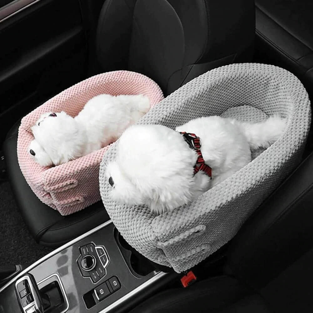 Two plush white dog toys in pink and gray car seat pet beds, placed on a car's front seats. Ideal for pet travel accessories and car safety.