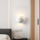 Modern white wall sconce in minimalist bedroom, featuring layered design, soft ambient lighting, and contemporary decor elements.