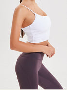 Woman in white crop top and purple leggings, showcasing activewear fashion. Fitness apparel, stylish workout clothing, comfortable gym outfit.