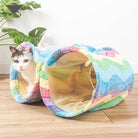 Colorful cat tunnel with a white and gray cat peeking out, featuring a zigzag pattern. Perfect pet play accessory for indoor cats.