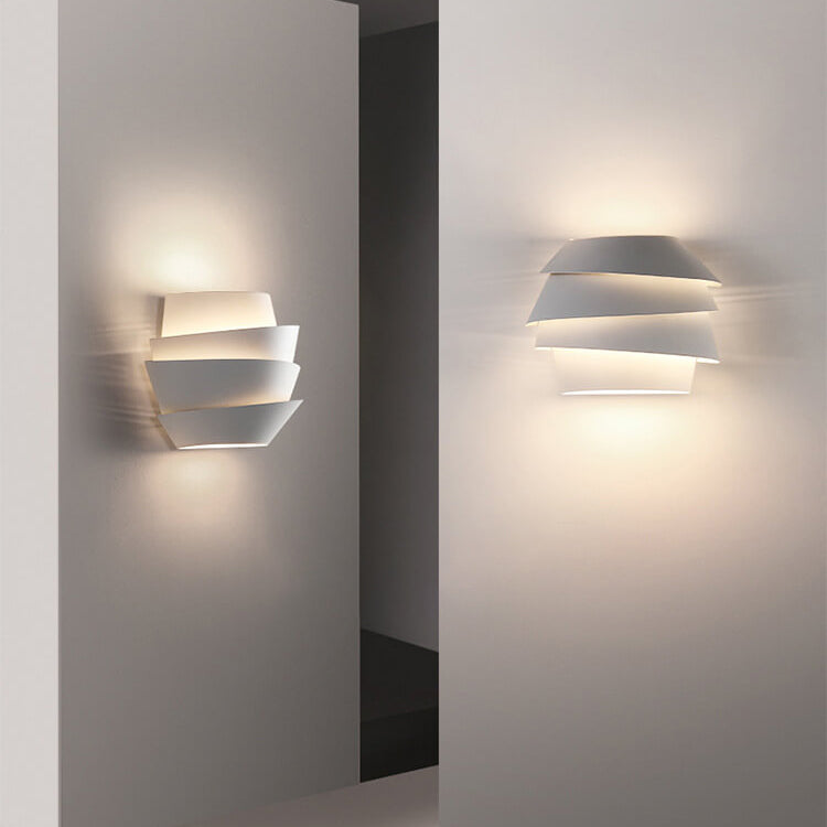 Modern white wall sconce with layered design, emitting soft ambient light. Contemporary home lighting fixture, minimalist decor, energy-efficient.