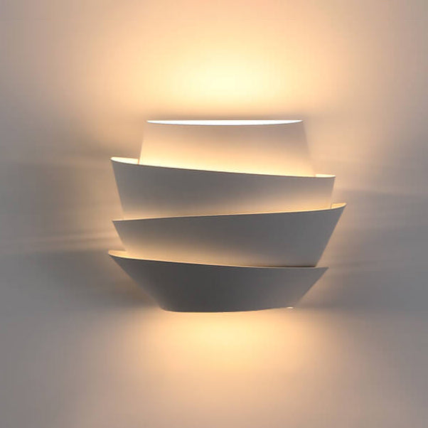 Modern white wall sconce with layered design, emitting warm ambient light. Contemporary home lighting fixture, stylish interior decor.