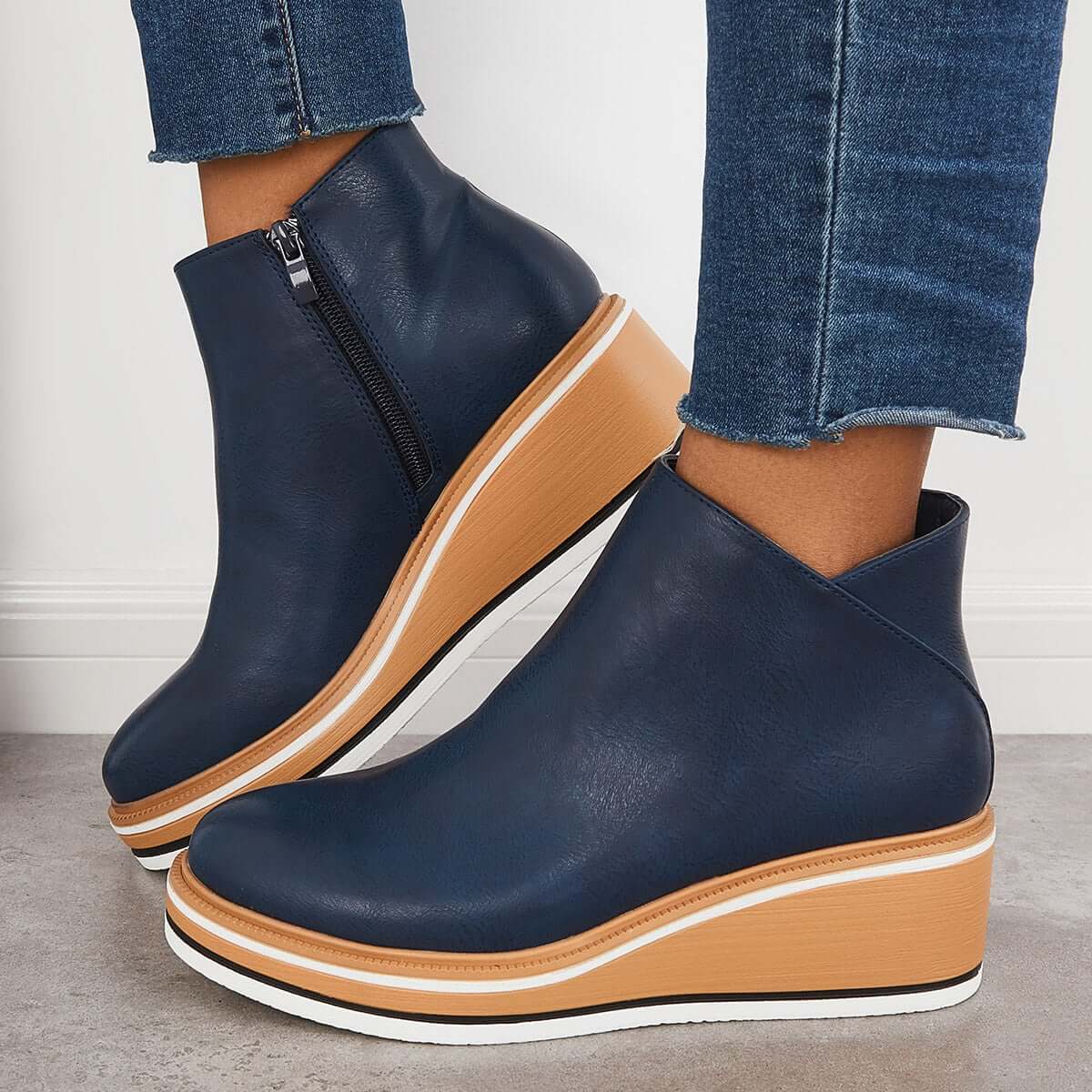 Navy blue wedge ankle boots with side zipper, paired with frayed hem jeans. Fashionable women's footwear, casual style, comfortable platform shoes.