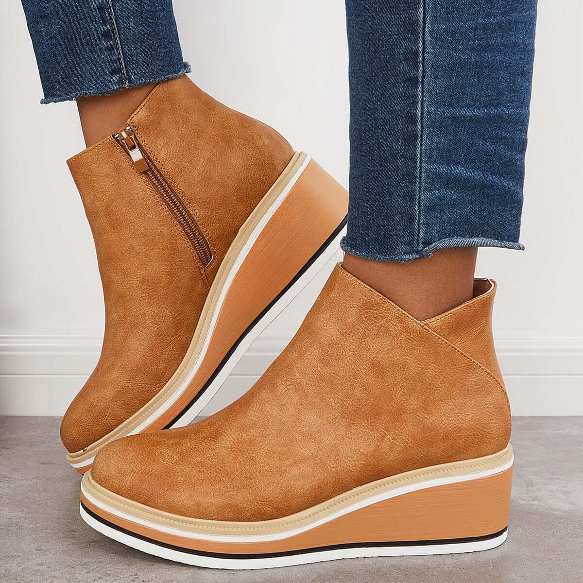 Tan wedge ankle boots with side zipper, paired with blue jeans. Stylish women's footwear, perfect for casual outfits. Fashionable and comfortable design.