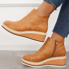 Tan leather wedge ankle boots with side zipper, paired with blue jeans. Fashionable women's footwear, casual style, comfortable design.