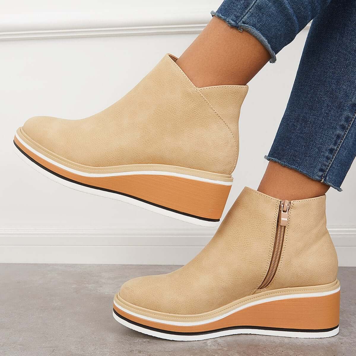 Beige platform ankle boots with side zippers, worn with blue jeans. Fashionable women's footwear, casual style, comfortable design.