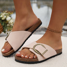 Women's beige leather sandals with large gold buckle, cork sole, and black rubber outsole, perfect for summer fashion and casual wear.