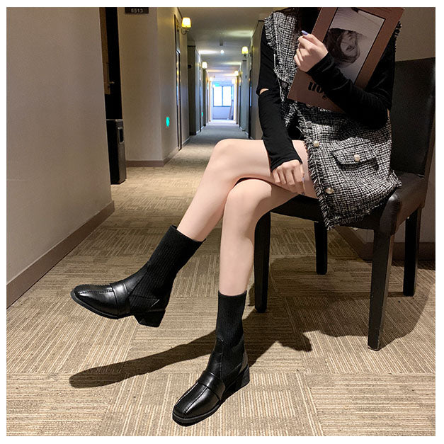 Fashionable woman in a tweed dress and black loafers sitting in a modern hallway, holding a magazine. Trendy fall outfit, stylish footwear.