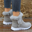 Gray faux fur ankle boots with white soles, worn with rolled-up jeans, on a wooden floor background. Stylish winter footwear for women.