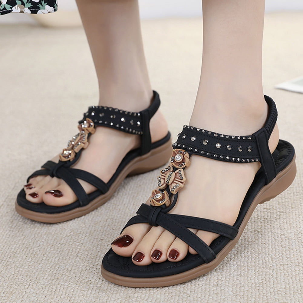 Women's black sandals with rhinestone embellishments and butterfly accents, featuring a comfortable flat sole. Perfect for casual summer wear.