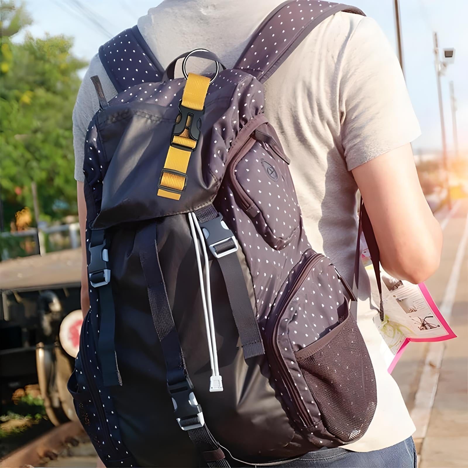 Person wearing a polka dot backpack with yellow strap, standing on a train platform. Travel gear, outdoor adventure, stylish backpack.