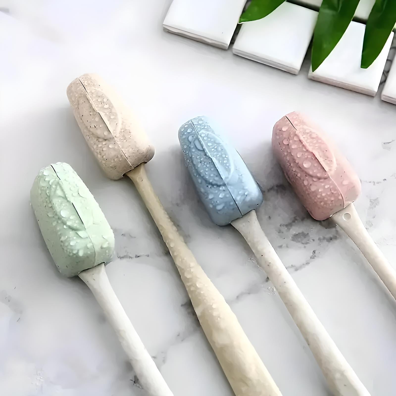 Four eco-friendly silicone toilet brushes in pastel colors with water droplets, displayed on a marble surface, next to green leaves and white tiles.