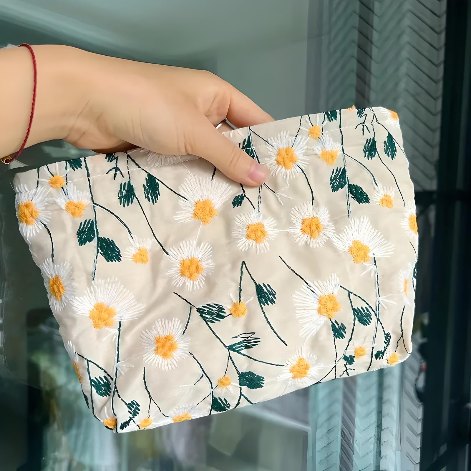 Hand holding a floral embroidered clutch bag with white and yellow daisy patterns, perfect for summer fashion accessories and casual outings.