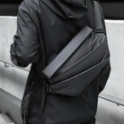 Man wearing sleek black crossbody bag with modern design, adjustable strap, and waterproof material. Ideal for urban travel and daily use.