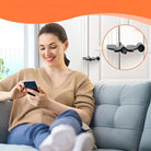 Woman using smartphone on couch with smart home security camera in background; wireless indoor surveillance device; modern home technology.