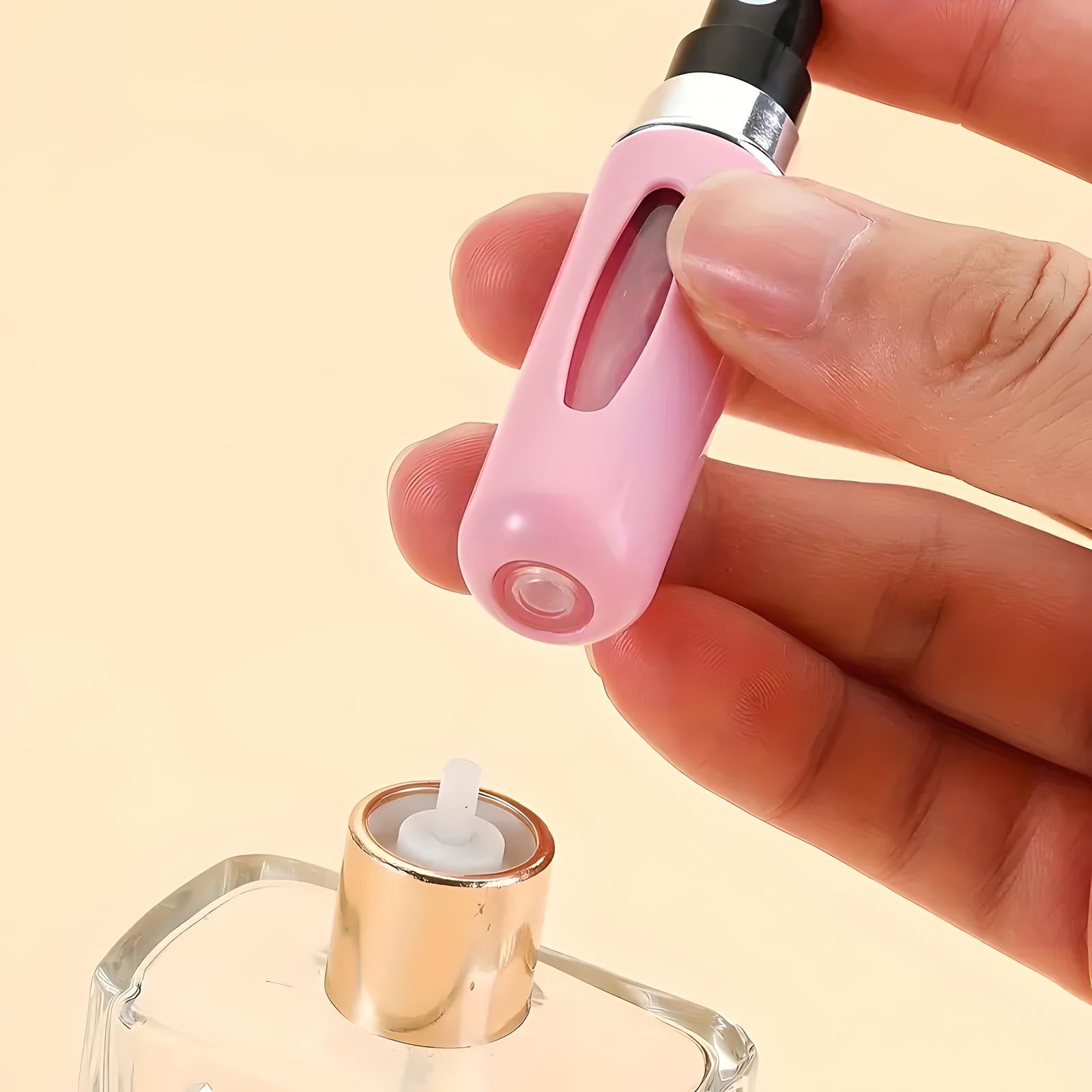 Hand holding pink perfume atomizer bottle, refilling from glass perfume bottle with gold cap. Portable travel spray container for fragrance.