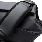 Close-up of a sleek black waterproof backpack with adjustable padded shoulder straps, ideal for travel and outdoor activities. Durable and stylish design.