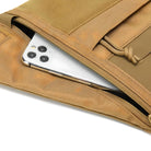 Tan tactical backpack with a smartphone partially visible in the front zippered pocket, showcasing durable fabric and secure storage.