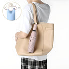 Person holding a beige tote bag with a pink compact umbrella attached. Inset shows 360-degree rotating hook. Fashionable accessory, practical design.