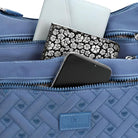 Blue quilted handbag with multiple zippered compartments, featuring a smartphone, floral-patterned wallet, and a white notebook.