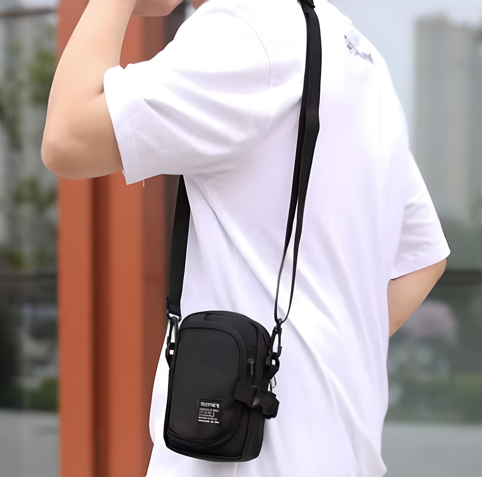 Man wearing a white t-shirt with a black crossbody bag, featuring adjustable strap and front pocket, ideal for urban fashion and travel essentials.