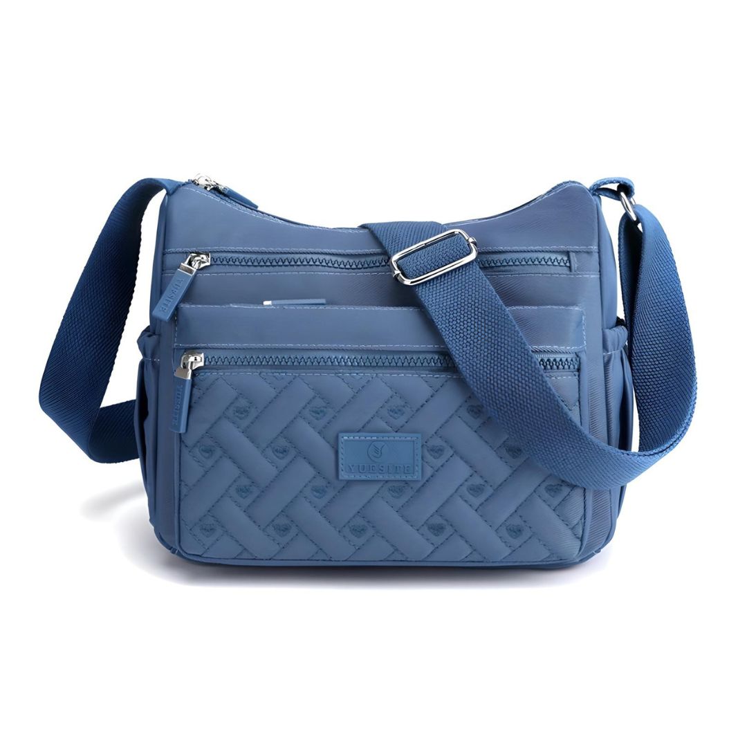 Blue crossbody bag with quilted design, adjustable strap, and multiple zippered compartments. Stylish women's handbag for everyday use.