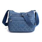 Blue crossbody bag with quilted design, adjustable strap, and multiple zippered compartments. Stylish women's handbag for everyday use.