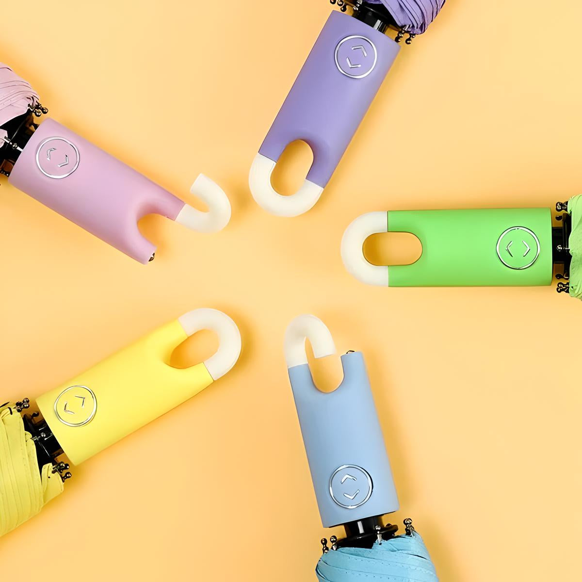 Colorful compact umbrellas with ergonomic handles arranged in a circle on a yellow background. Pastel shades include purple, green, blue, and yellow.