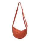 Orange crescent-shaped crossbody bag with adjustable strap, minimalist design, ideal for casual wear. Perfect for fashion-forward, everyday use.