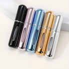 Five sleek, metallic travel perfume atomizers in black, pink, blue, gold, and silver, ideal for portable fragrance storage and stylish on-the-go use.