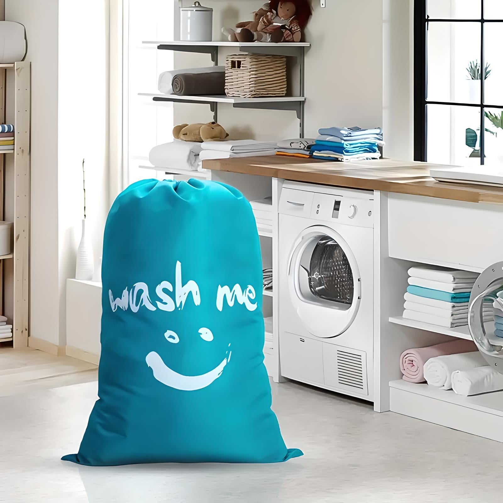 Large blue laundry bag with "wash me" text in modern laundry room; washing machine, shelves with folded towels, and natural light.