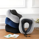 Stacked memory foam neck pillows in gray, blue, and black on a wooden table, ideal for travel comfort and ergonomic support.