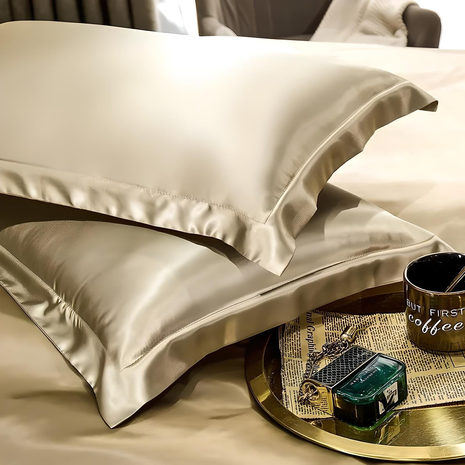 Luxurious silk pillowcases on a bed with a gold tray, featuring a coffee mug, newspaper, and perfume bottle. Elegant bedroom decor, soft bedding.