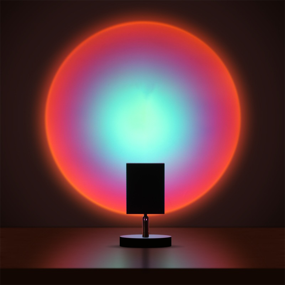 Modern LED sunset projection lamp casting vibrant red, orange, and blue circular light on wall; ideal for ambient home decor and mood lighting.