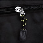 Close-up of a black zipper with a yellow and black braided pull cord on a textured fabric bag. Durable zipper design, travel bag accessory.