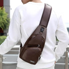 Man wearing a stylish brown leather crossbody sling bag with multiple zippered compartments, perfect for travel and casual outings.