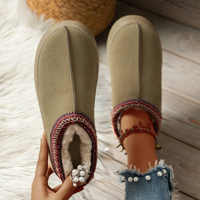 Cozy women's winter slippers with faux fur lining, embroidered trim, and pearl-accented denim jeans. Perfect for warm, stylish indoor wear.