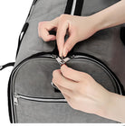 Hands zipping a gray travel duffel bag with black accents, showcasing durable zippers and spacious design. Ideal for travel, gym, or weekend trips.