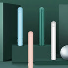 Modern minimalist humidifiers in pastel colors on a green background, featuring sleek cylindrical design. Ideal for home decor and air purification.