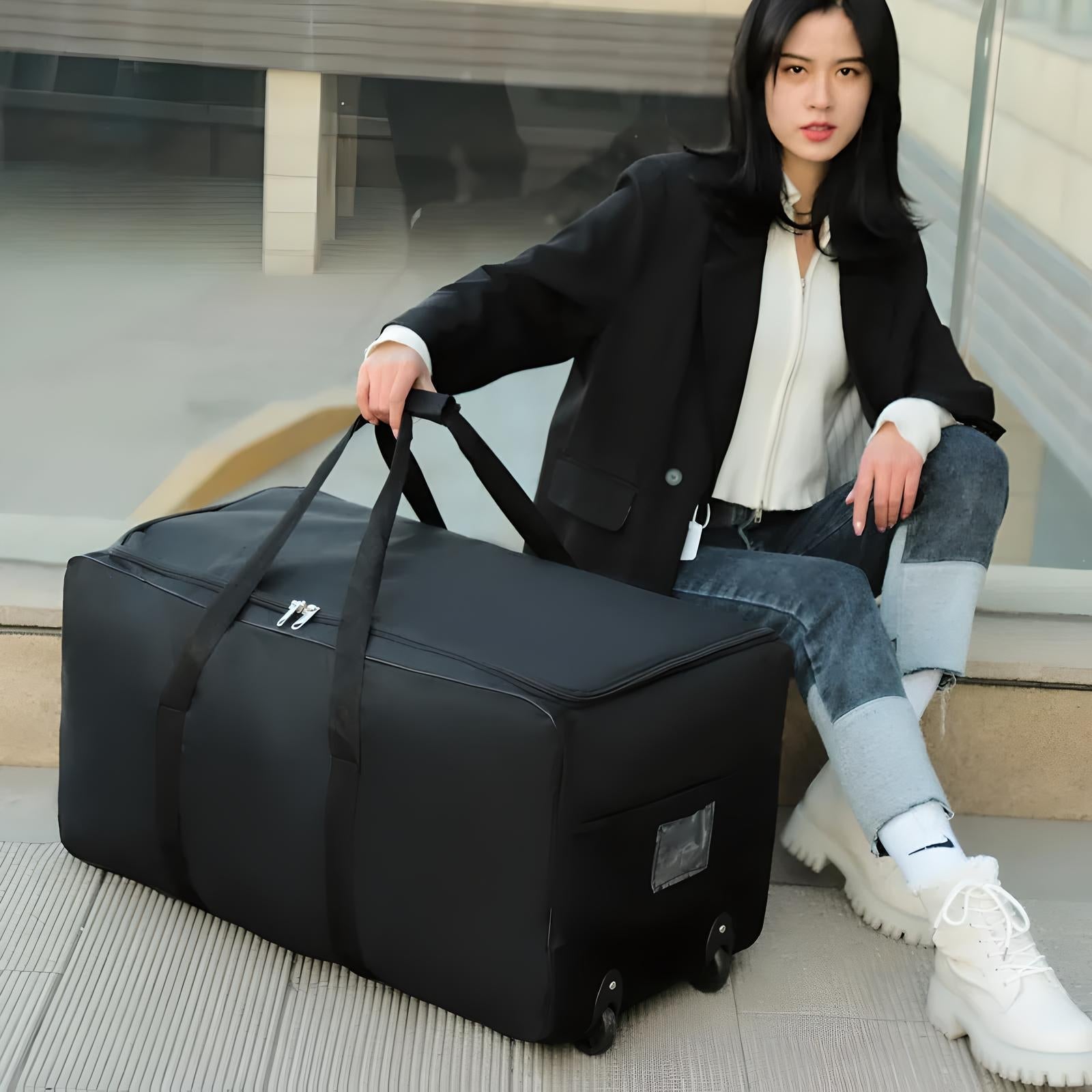 Woman sitting with large black wheeled duffel bag, wearing casual outfit. Travel luggage, durable design, convenient for trips.