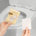 Flushable toilet seat covers in packaging, held by hands over a toilet seat. Convenient hygiene solution, travel-friendly, disposable, eco-friendly.