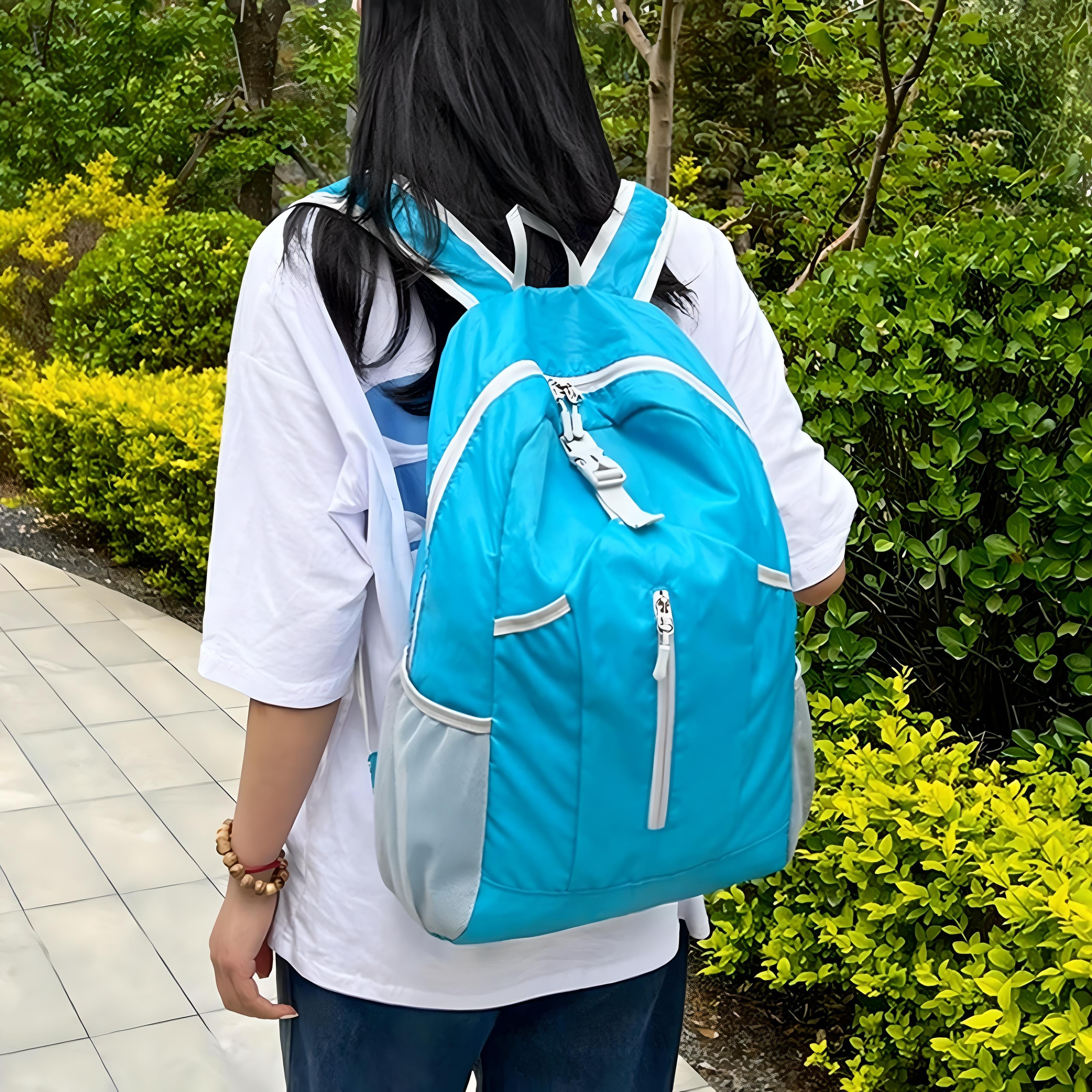 Woman wearing a blue backpack walking on a tiled path surrounded by lush greenery. Outdoor fashion, casual style, travel accessory.