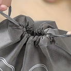 Close-up of a gray mesh drawstring bag being tightened, showcasing durable fabric and sturdy cords. Ideal for travel, storage, and organization.