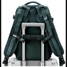 Green travel backpack with adjustable straps, securely attached to a silver rolling suitcase handle. Ideal for travel, luggage organization, and convenience.