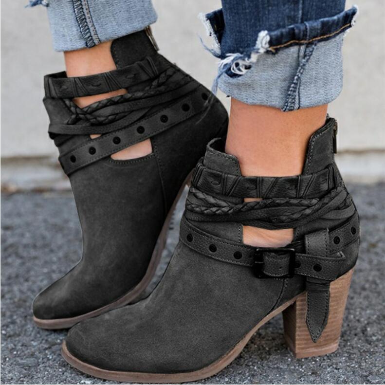 Stylish black ankle boots with braided straps and chunky heels, paired with rolled-up jeans. Perfect for casual fashion and fall footwear trends.