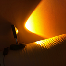 Modern sunset projection lamp casting warm yellow light on a textured wall, creating a cozy ambiance. Ideal for home decor and mood lighting.