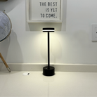 Modern black LED table lamp on a white countertop, illuminating a minimalist space. Ideal for contemporary home decor and efficient lighting solutions.