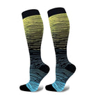 Colorful gradient knee-high compression socks with black, yellow, and blue stripes, designed for athletic performance and improved circulation.