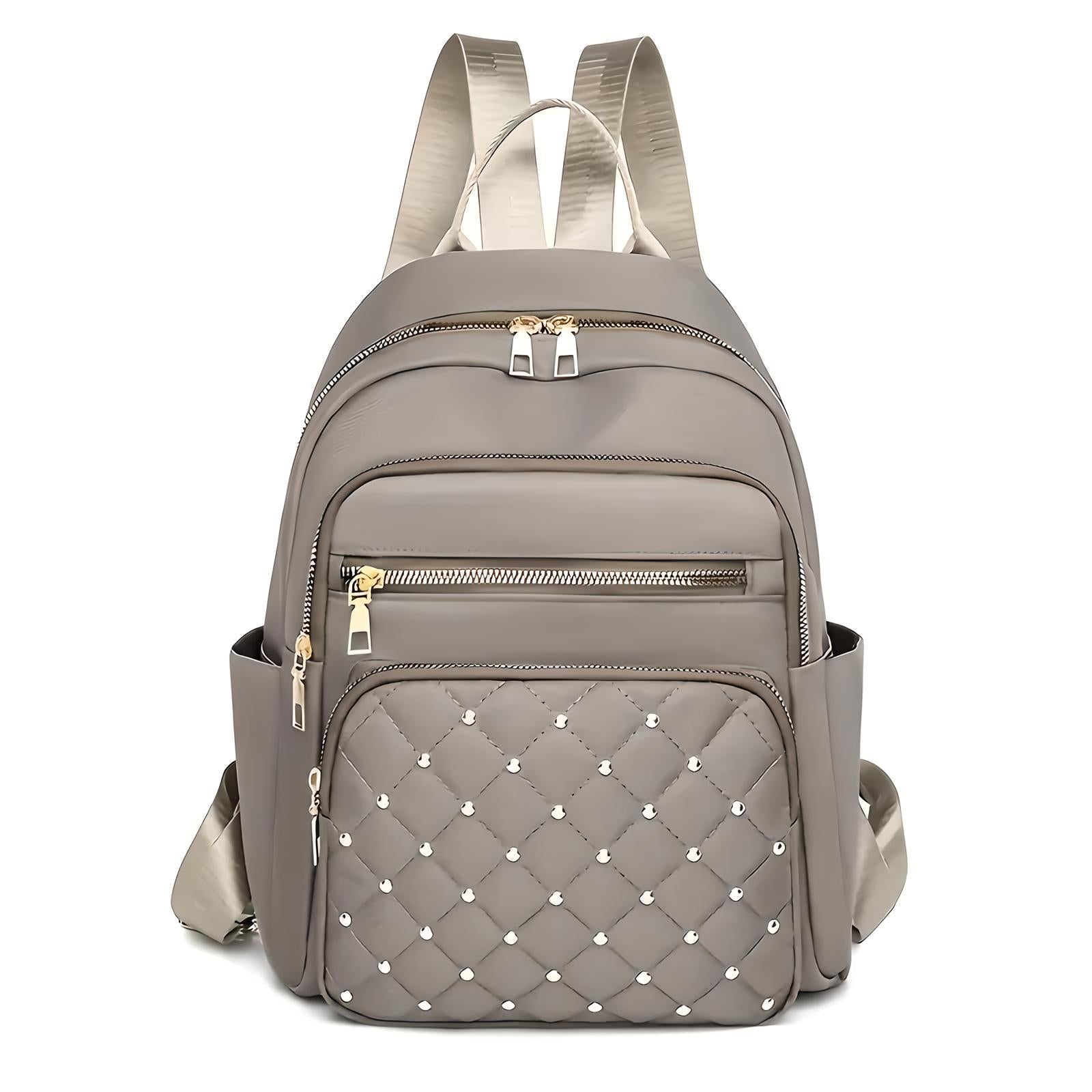 Stylish taupe backpack with quilted front pocket, gold zippers, and adjustable straps. Perfect for travel, school, or daily use. Fashionable and functional.